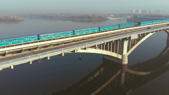 Two Subway Trains Crossing a Wide River Over the Bridge.