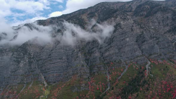 Aerial view of colorful foliage panning across cliffs on mountain