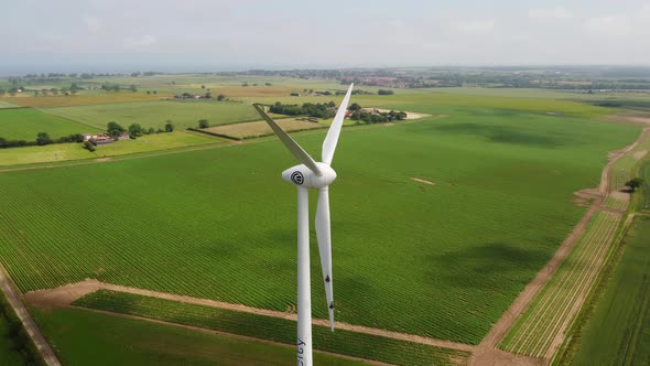 Drone Shot Circling Around a Large Wind Turbine in Open Green Fields