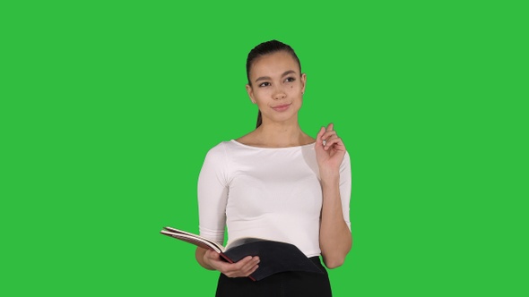 Young business woman walking and reading from notebook