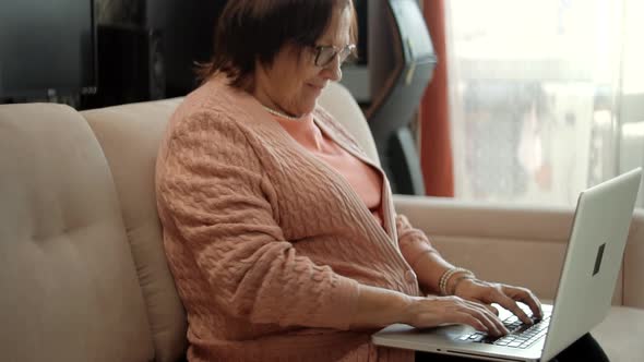 Senior Woman Using Laptop Computer.Senior Woman Hands Typing On Laptop Keyboard.Online Meeting