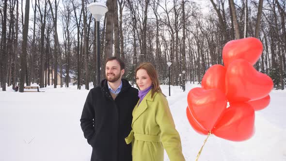 Young Cute Couple Walks in the Park with Balloons. Love Story.