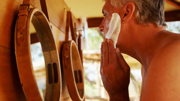 Man applying shaving cream on his face in cottage