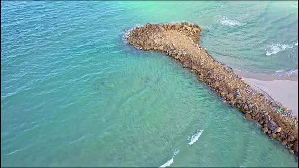 Drone Flies From Pier To Open Azure Ocean and Rocky Hills