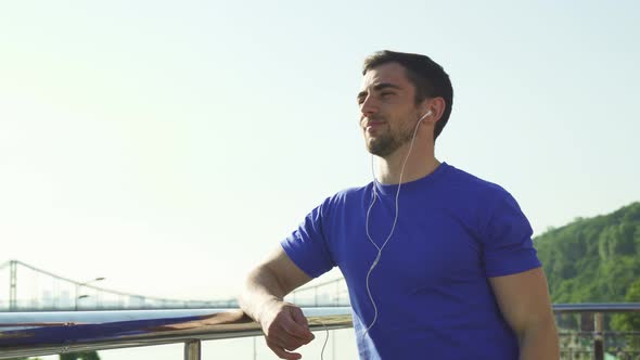 Happy Handsome Man Enjoying Listening To Music Outdoors After Working Out