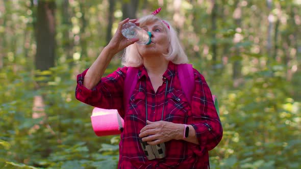 Tired Thirsty Senior Old Caucasian Hiker Grandmother Relaxing Drinking Water in Forest After Walk