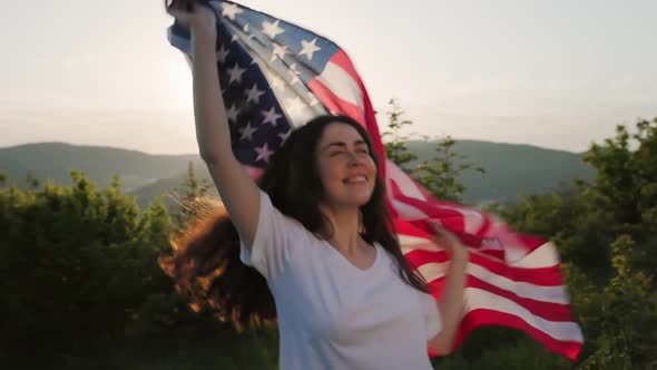 A young beautiful woman goes singing, dancing and waving the American flag