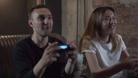 Handsome Adorable Young Guy with His Girlfrend Having Fun Playing Video Games Drinking Beer with