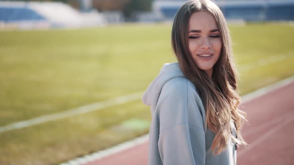Slow Motion Cute Caucasian Girl Posing at the Stadium in a Gray Tracksuit