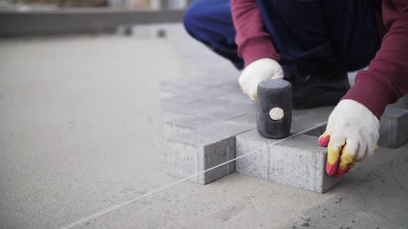 footage of builder lays paving slabs