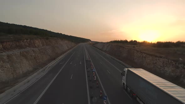 Drone Follows Long Haul Semi Truck on a Highway at Sunset