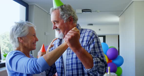 Senior couple wearing party hats dancing at birthday party 4k
