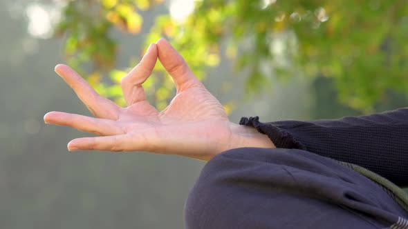 Woman in yoga pose puts and removes hand with nature background