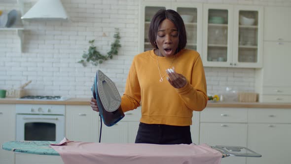 Black Teenage Girl Ironing Clothes with Iron at Home