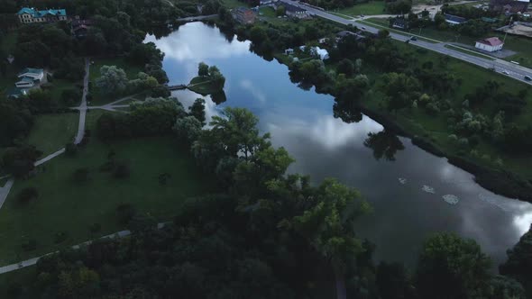 City park with a reservoir. A bridge leads to the island. Aerial photography at dusk.