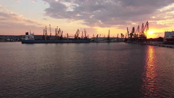 Aerial View of Cargo Ship Bulk Carrier is Loaded with Grain of Wheat in Port at Sunset