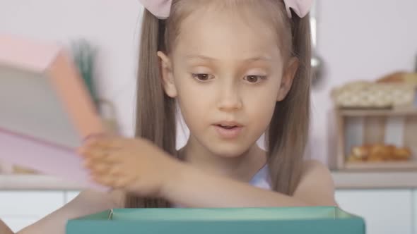 Close-up Face of Amazed Caucasian Girl Opening Glowing Gift and Looking Inside, Portrait of Charming