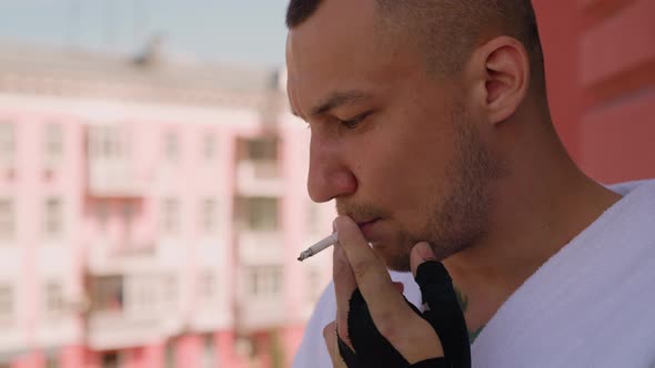 Attractive Man Smokes Cigarette Thinking on Terrace of Hotel