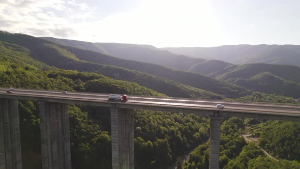 Evening Truck Traffic on Highway Bridge Against Green Hills and Deep Valley