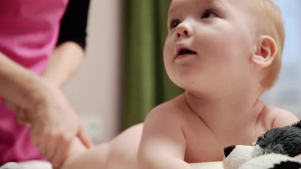 The masseuse gives a leg and foot massage to baby (boy) 13