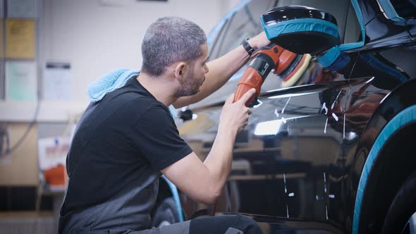 An Experienced Detailing Studio Worker Polishing a Car