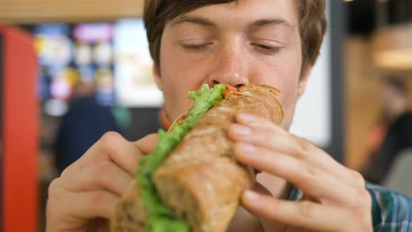 Guy Eats Hot Dog and Enjoys Lunch Sitting in Shopping Mall