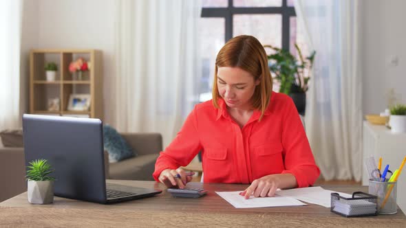 Woman with Calculator and Papers Working at Home