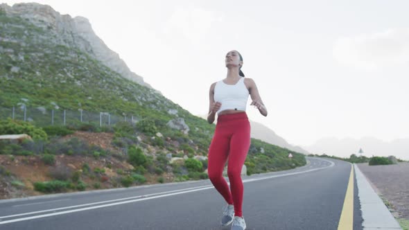 Mixed race woman taking a break from running on a country road