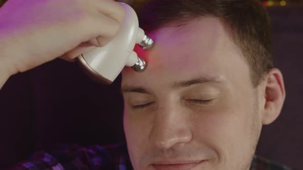 Young Man Using 3d Massager for Face