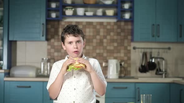 child at home in the kitchen at the table eats a delicious cooked Burger