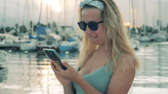 A Girl Types on a Phone While Resting in Docks