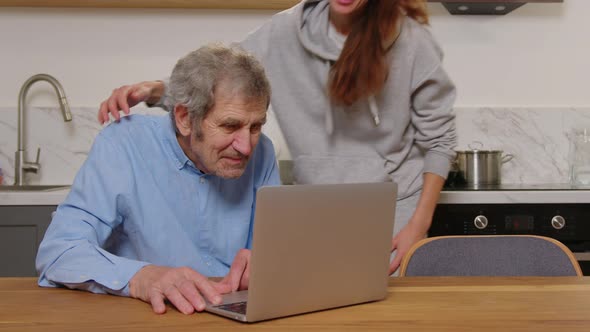 Happy Grandfather and Daughter Hugging Looking at Something on a Laptop at Home