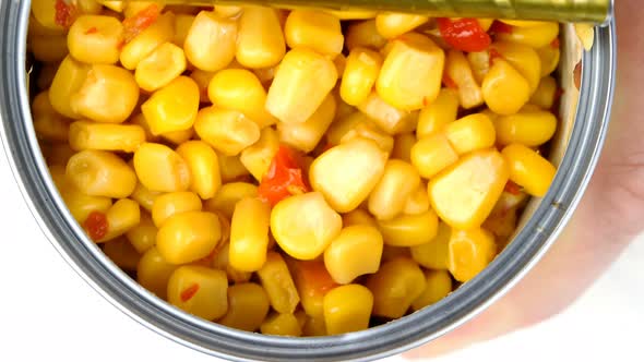 Hand Opens Metallic Tin Can of Marinated Sweet Corn with Vegetables