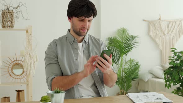 Businessman is Using a Smartphone and Smiling While Working in Office