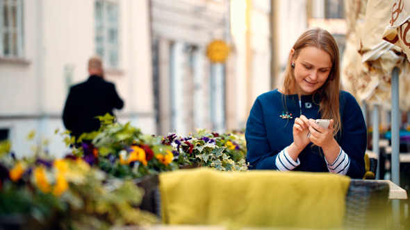 Woman Using Her Smartphone Sitting In Outdoor Cafe