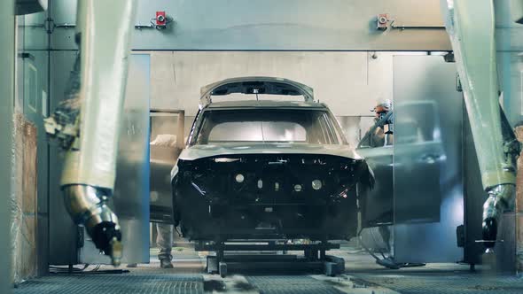 Car Factory Workers Spray Painting a Car Black at a Car Manufacturing Plant