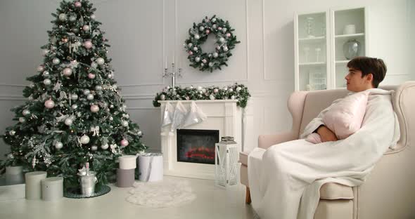 Young Man Sitting on Sofa, Basking By the Fireplace. Christmas Day