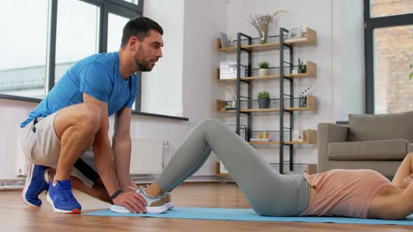 Woman with Personal Trainer Doing Sit Ups at Home
