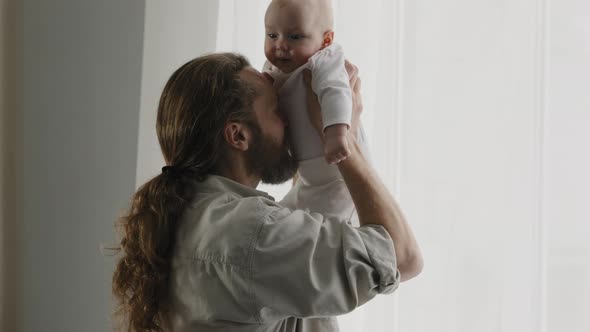 Caucasian Bearded Adult Father Throw Up Little Cute Smiling Son Daughter Infant Playing Together at