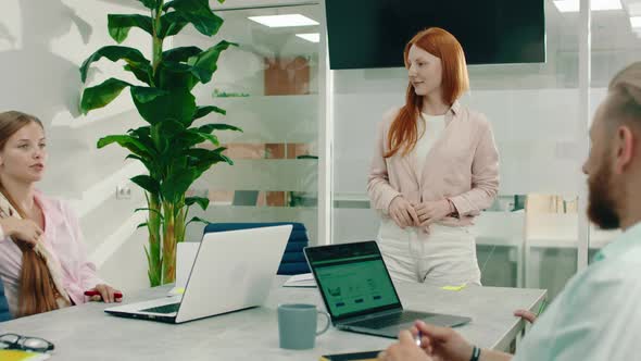 A Boss Looking Ginger Haired Woman is in an Office