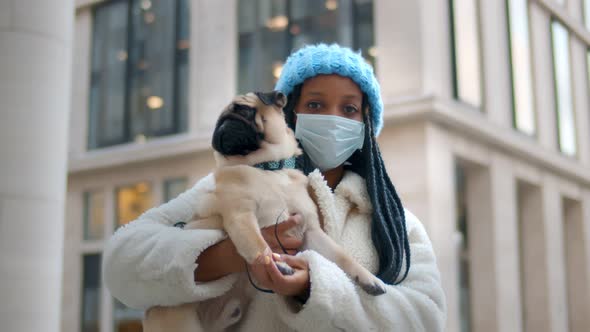 Afroamerican Woman in Protective Mask with Pug Dog on City Street