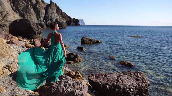 Side View a Young Beautiful Sensual Woman with Black Hair in a Long Mint Dress Posing on a Beach