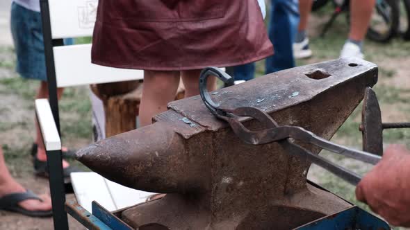 Close-up of forging a horseshoe. A blacksmith at a festival teaches  a girl to forge an horseshoe