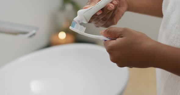 Midsection of african american woman brushing teeth in bathroom