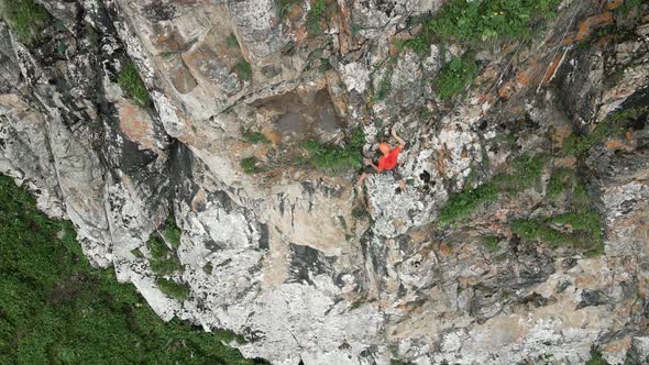 Man Athlette Climbing on the High Rock in the Mountains