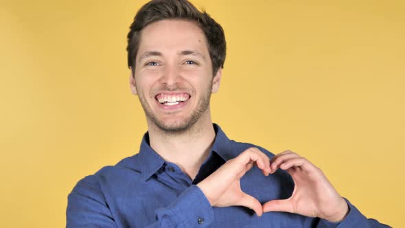 Handmade Heart By Young Man Isolated on Yellow Background