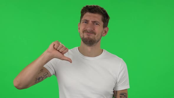 Portrait of Confident Guy Is Showing Thumbs Down Gesture. Green Screen