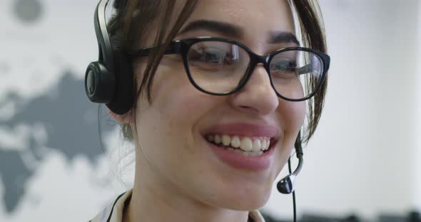 Close Up of Beautiful Young Operator Woman Standing and Wearing Headset at the Bright Office Space