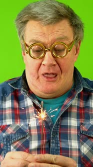 Caucasian Mature Adult Man Blows Hard on Sparkler and Wonders That He Cannot Extinguish It