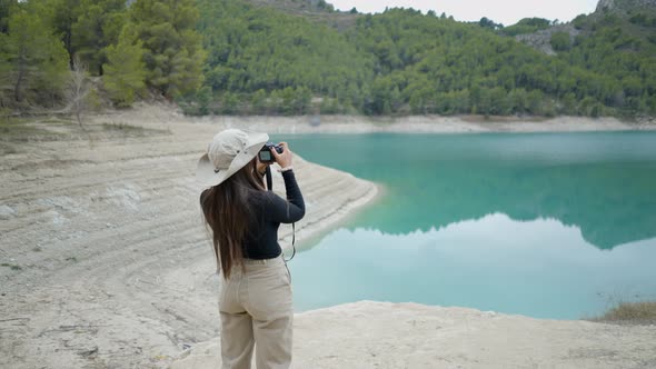 Young Woman Walks and Takes Pictures of Still Lake and Forest in Spain